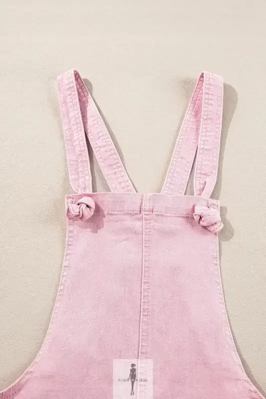 Pink denim romper with knotted straps and pockets, perfect for casual wear