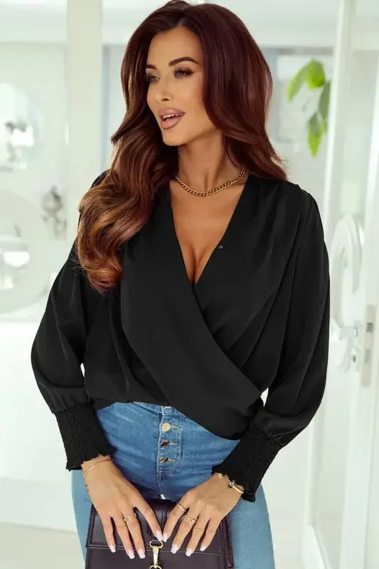 Woman in black solid surplice neck shirred cuffs draped blouse with jeans