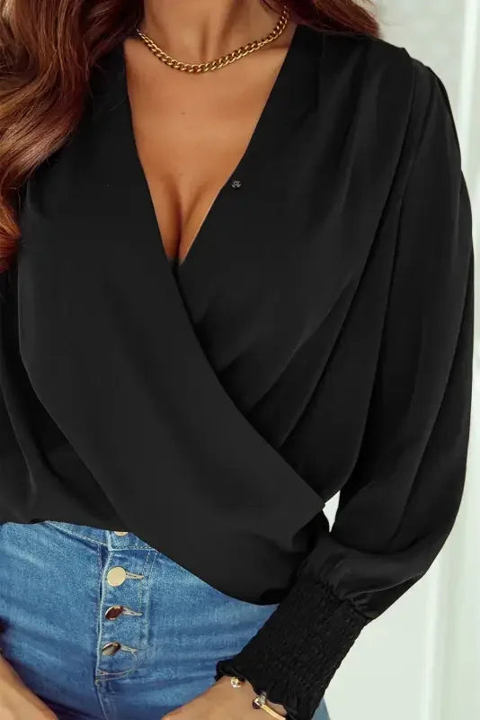 Black wrap blouse with solid surplice neck and shirred cuffs draped design