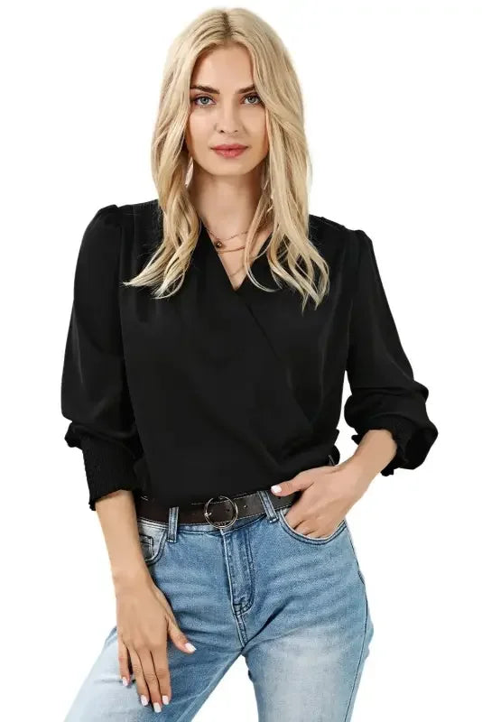 Woman in black blouse with solid surplice neck and shirred cuffs draped style