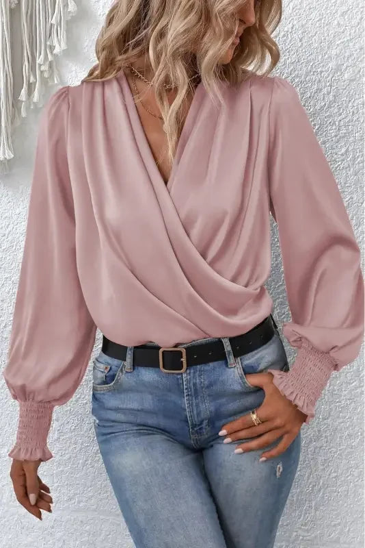 Woman wearing pink wrap blouse with solid surplice neck and shirred cuffs draped style