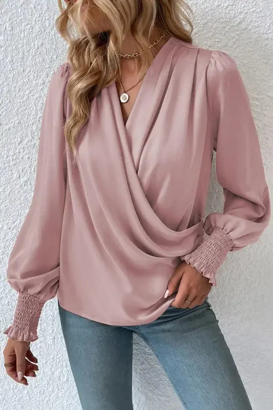 Pink long-sleeved wrap blouse featuring a solid surplice neck and shirred cuffs draped design