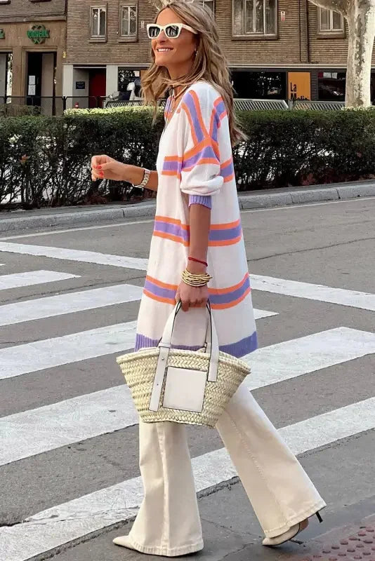 Woman wearing multicolor striped cardigan and straw tote bag in stylish outfit