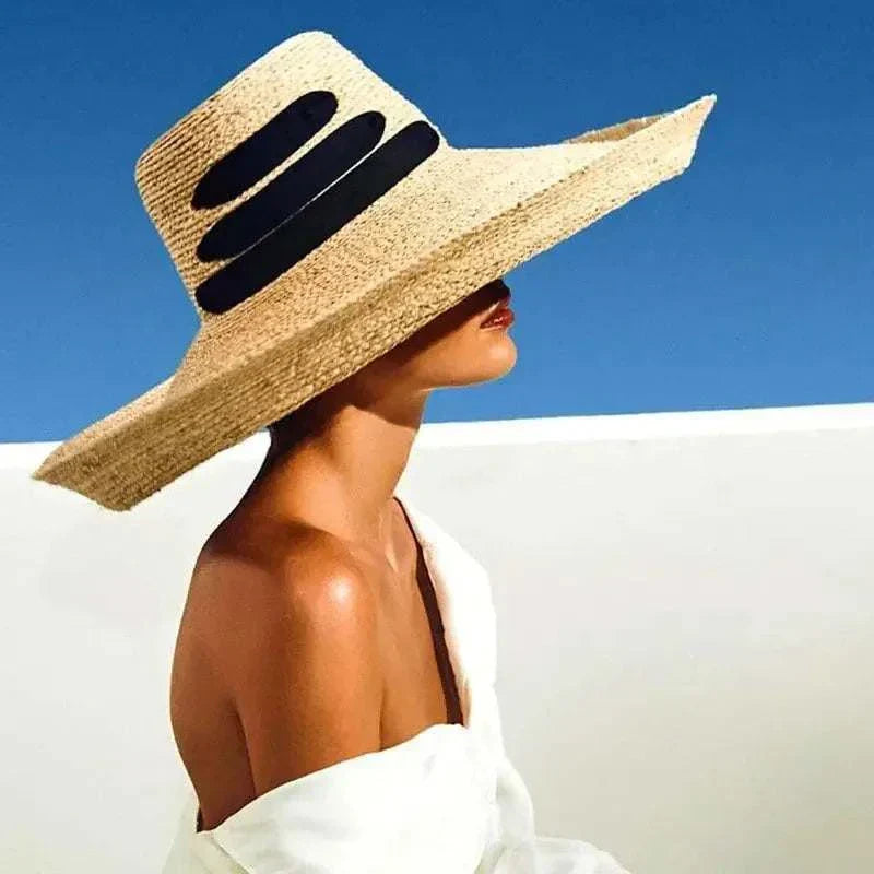 Woman wearing wide brim beach hat with black ribbon on blue sky background