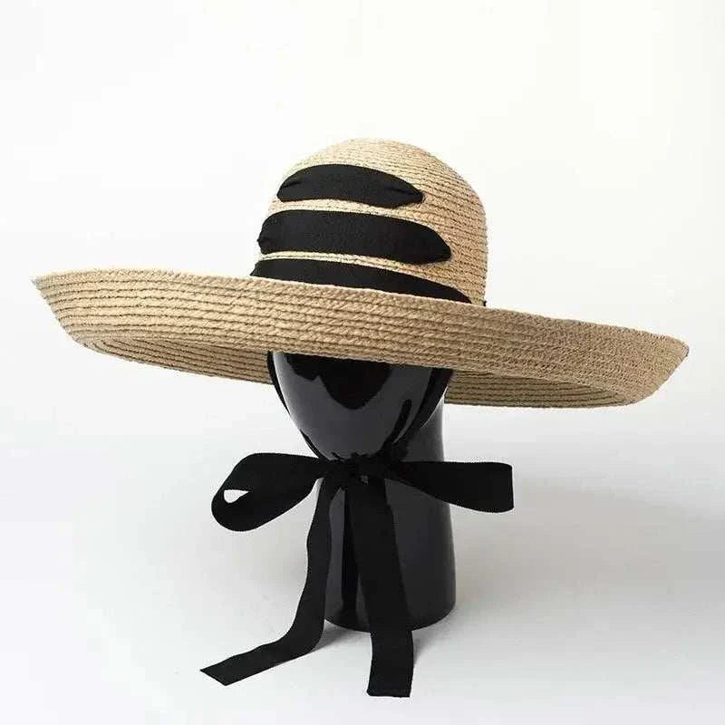Wide brim beach hat made of straw raffia with black ribbon bow and solid pattern