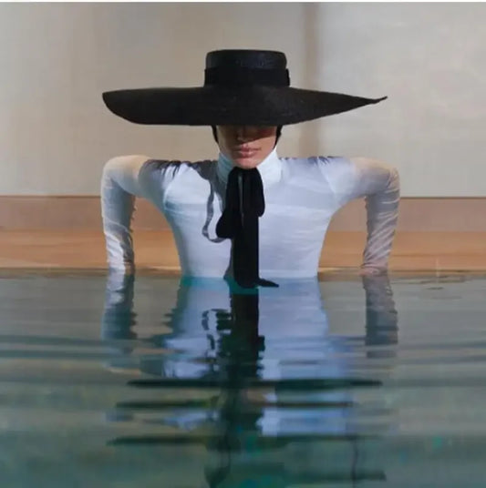Woman in water wearing black wind brim hat and tie showcasing wind brim style