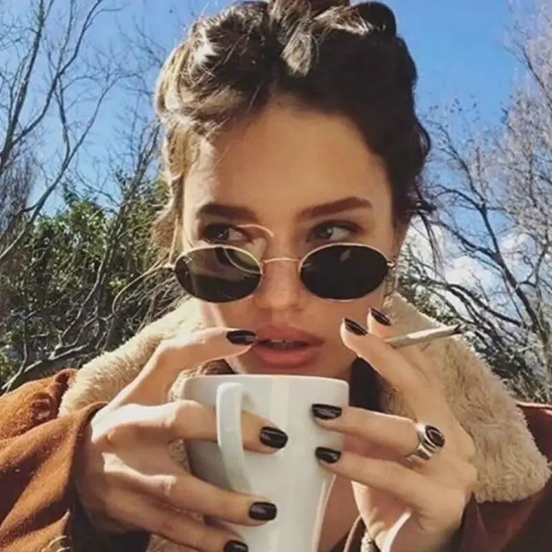 Woman with Gold Frame Street Oval Sunglasses, coffee, and cigarette outdoors