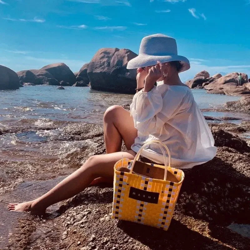 Yellow and black woven tote bag paired with ladies straw beach hat for a stylish beach look