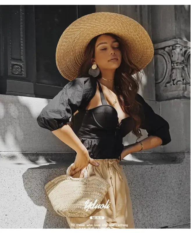 Woman wearing a wide brim straw hat and black top showcasing stylish wide brim straw hats