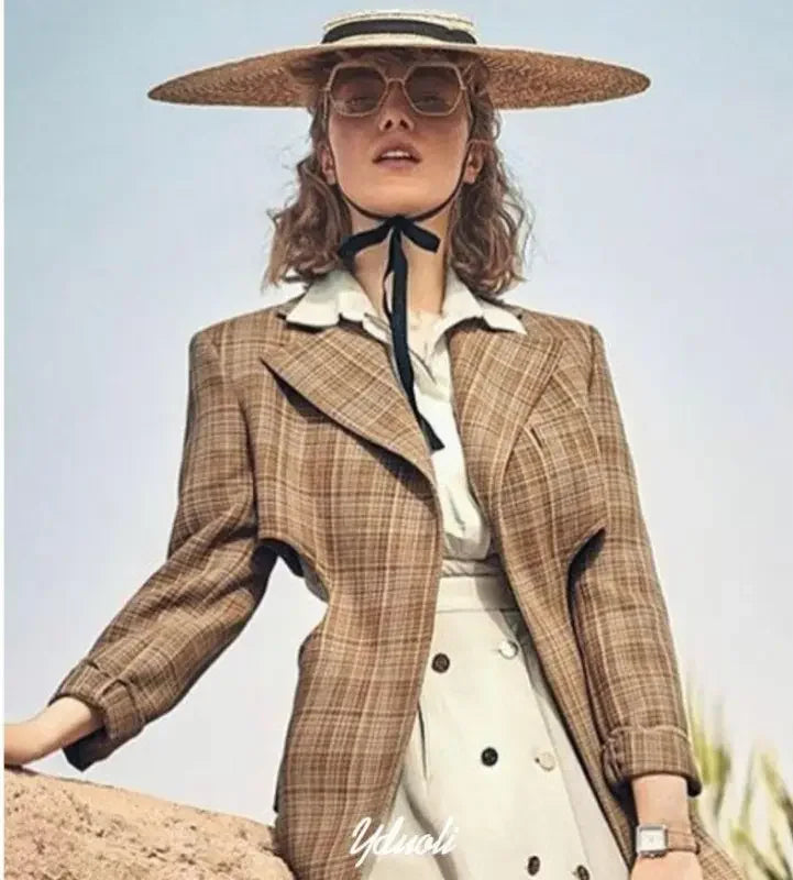 Woman’s plaid blazer outfit accessorized with wide brim straw hats for chic summer style