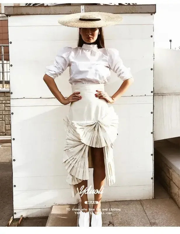 Woman in white skirt and blouse wearing a stylish wide brim straw hat