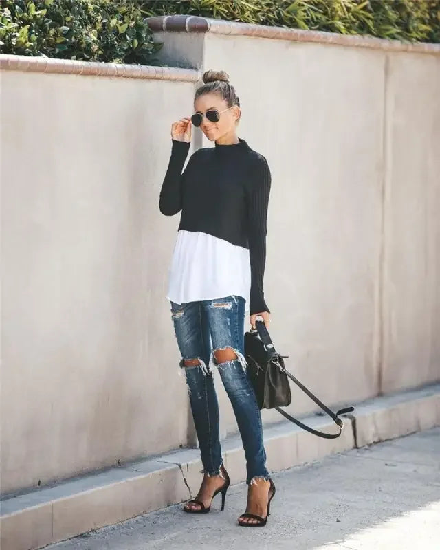Woman in ripped jeans and heels wearing a chic layered knit sweater shirt look