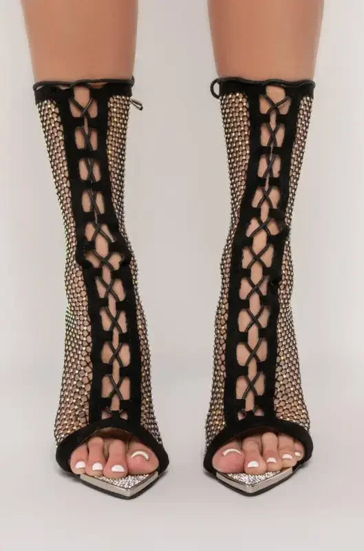 Black fishnet lace-up heels featuring eyelet rhinestone ankle design and embellishments