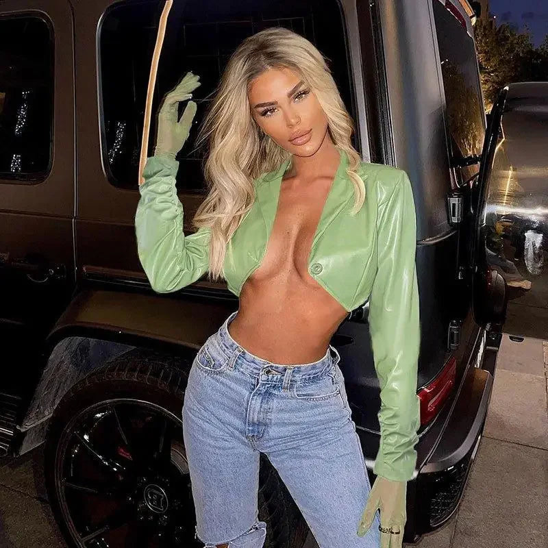 Blonde woman wearing a green leather irregular crop jacket and jeans showcasing style