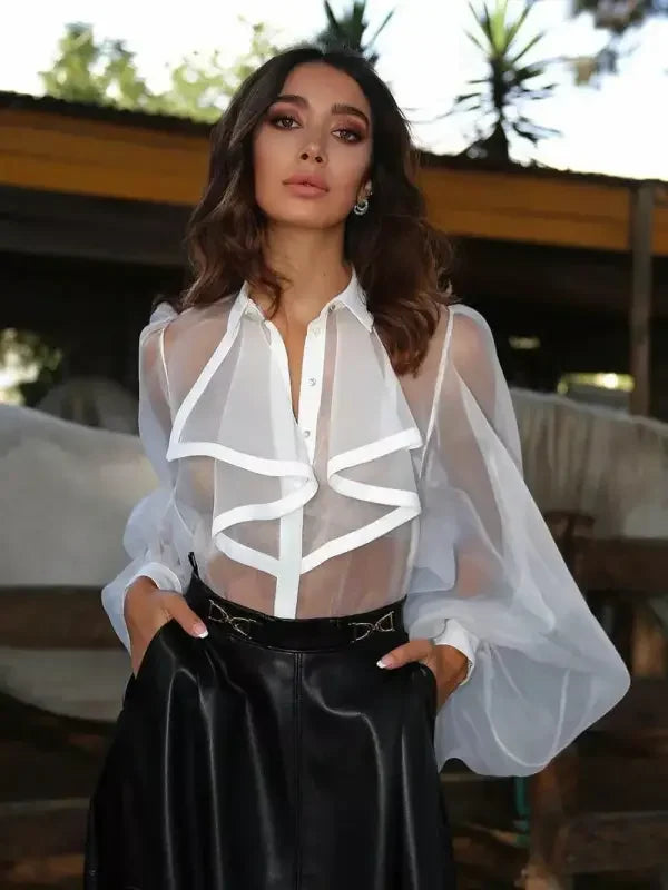 Woman in sheer white blouse with ruffles turndown collar and loose fit style