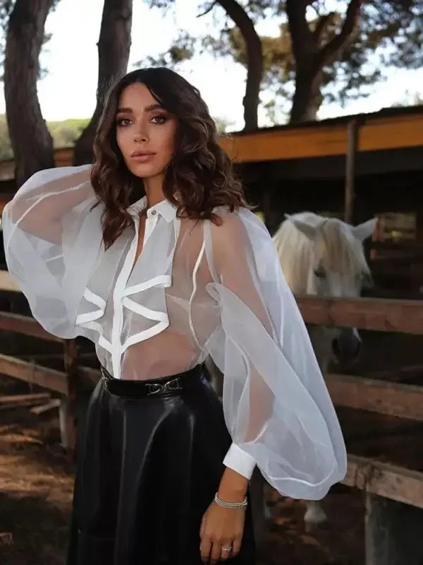 Woman wearing a ruffles turndown collar loose bodysuit in sheer white blouse and black skirt