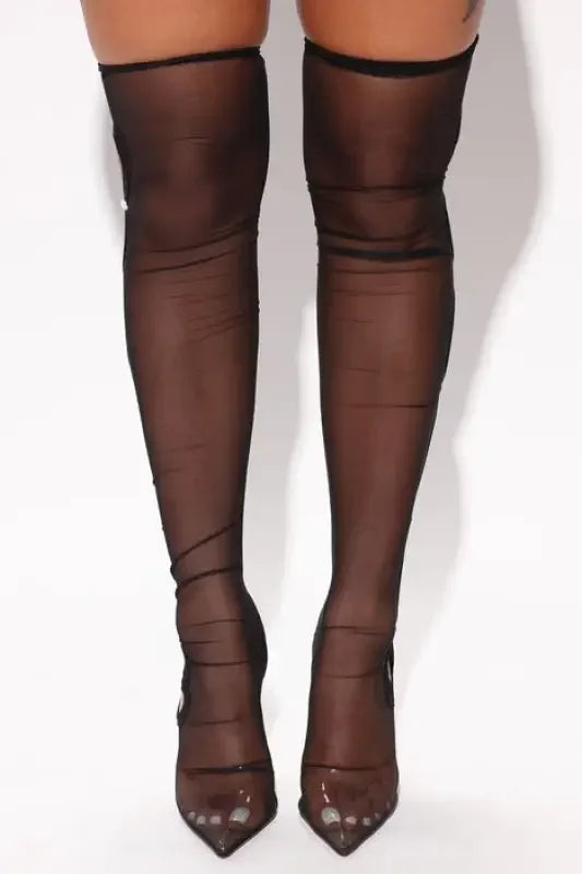 Elegant thigh-high sheer black stockings with pointed-toe heels for fashion runway over-the-knee style